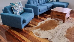 A living room with a blue sectional sofa, a wooden coffee table, and a cowhide rug. - Yungaburra Whitehouse 
Walking distance to village (100 metres)
2 ensuites (Yungaburra)
