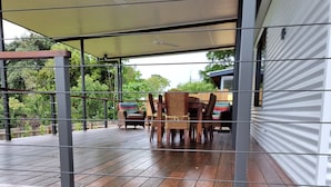 A covered patio area with a wooden deck, metal railings, and a table with chairs. - Yungaburra Whitehouse 
Walking distance to village (100 metres)
2 ensuites (Yungaburra)