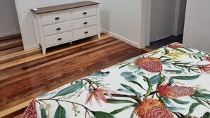 A bedroom with a wooden floor, a white dresser, a ceiling fan, and a door. - Yungaburra Whitehouse 
Walking distance to village (100 metres)
2 ensuites (Yungaburra)