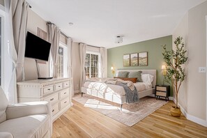 A bedroom with a bed, a dresser, a TV, and a plant. - The Octagon & APT - Hot tub, Game room, 1.8 miles to Lake Michigan beach (Pentwater)