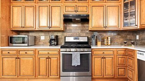 Una cocina con armarios de madera, estufa de acero inoxidable, microondas y lavavajillas.
