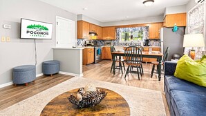 Una cocina moderna con armarios de madera, un comedor con mesa y sillas, y una sala de estar con sofá y una mesa de centro.