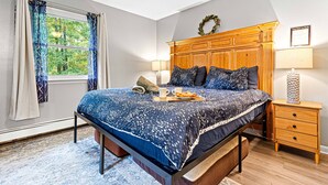 Un dormitorio con cama, mesita de noche y ventana con cortinas.