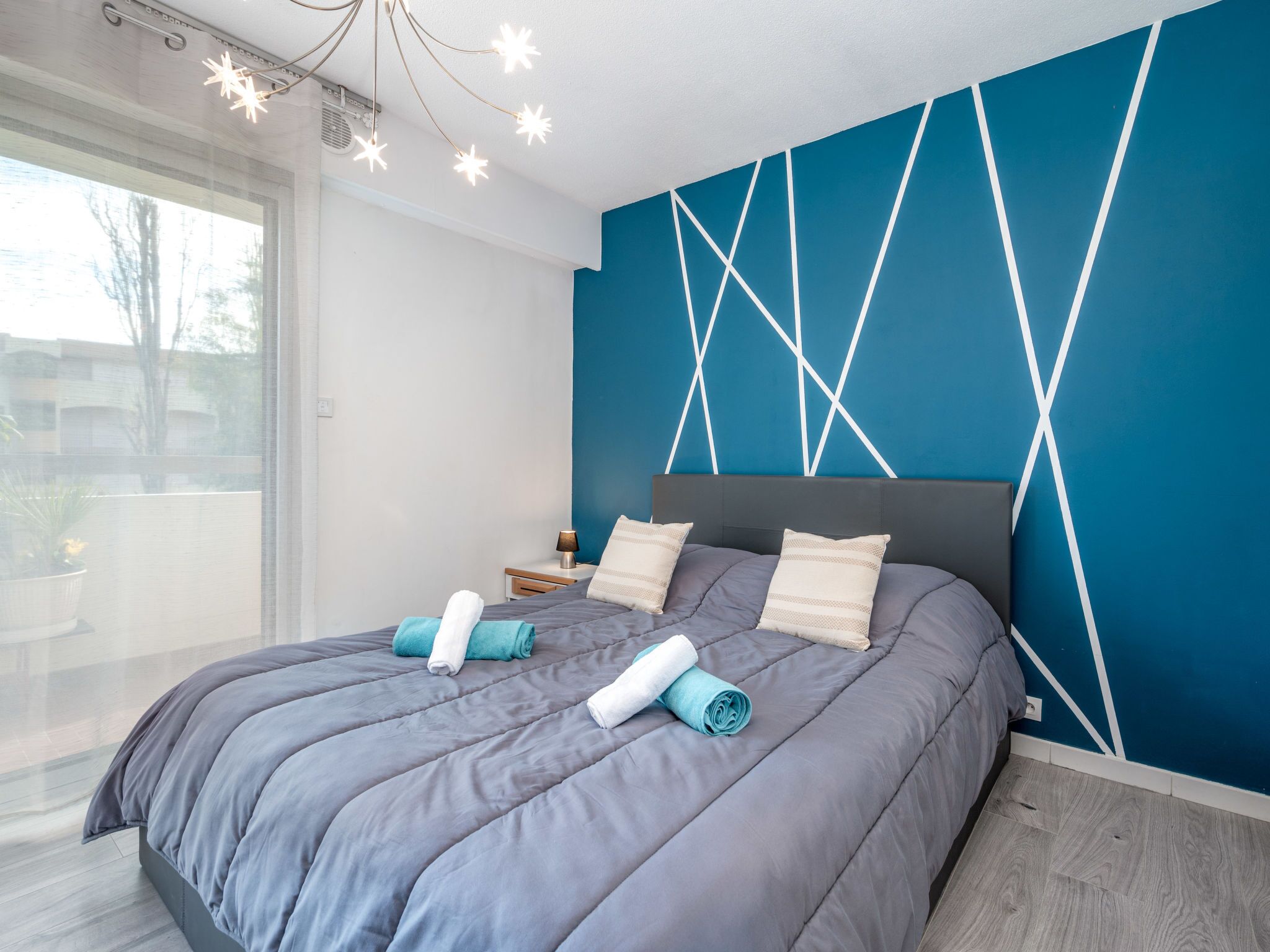 Un dormitorio moderno con una cama grande, una mesita de noche y una pared azul de acento.