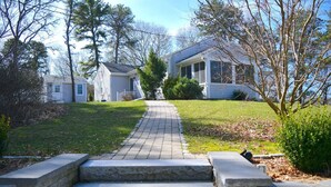 A residential area with a paved pathway leading to a house with a porch.