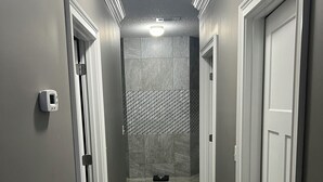 A hallway with grey walls, a wooden floor, and a tiled wall at the end.