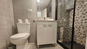 Un baño moderno con inodoro, tocador y zona de ducha.