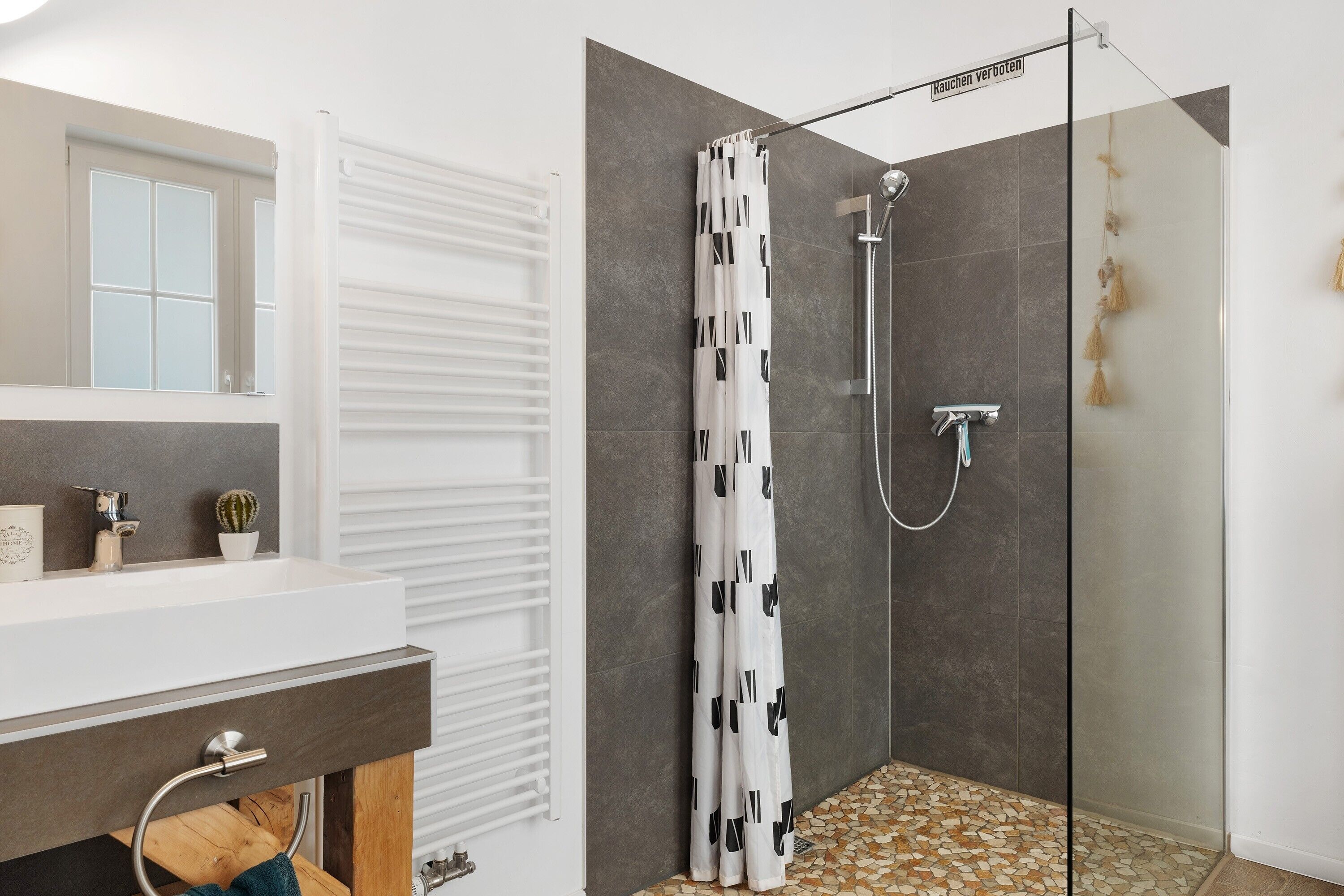 Un baño moderno con ducha, lavabo y espejo.