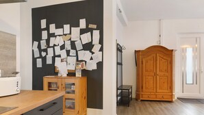 A kitchen with a wooden countertop, a blackboard with papers, a cabinet, and a wooden wardrobe.