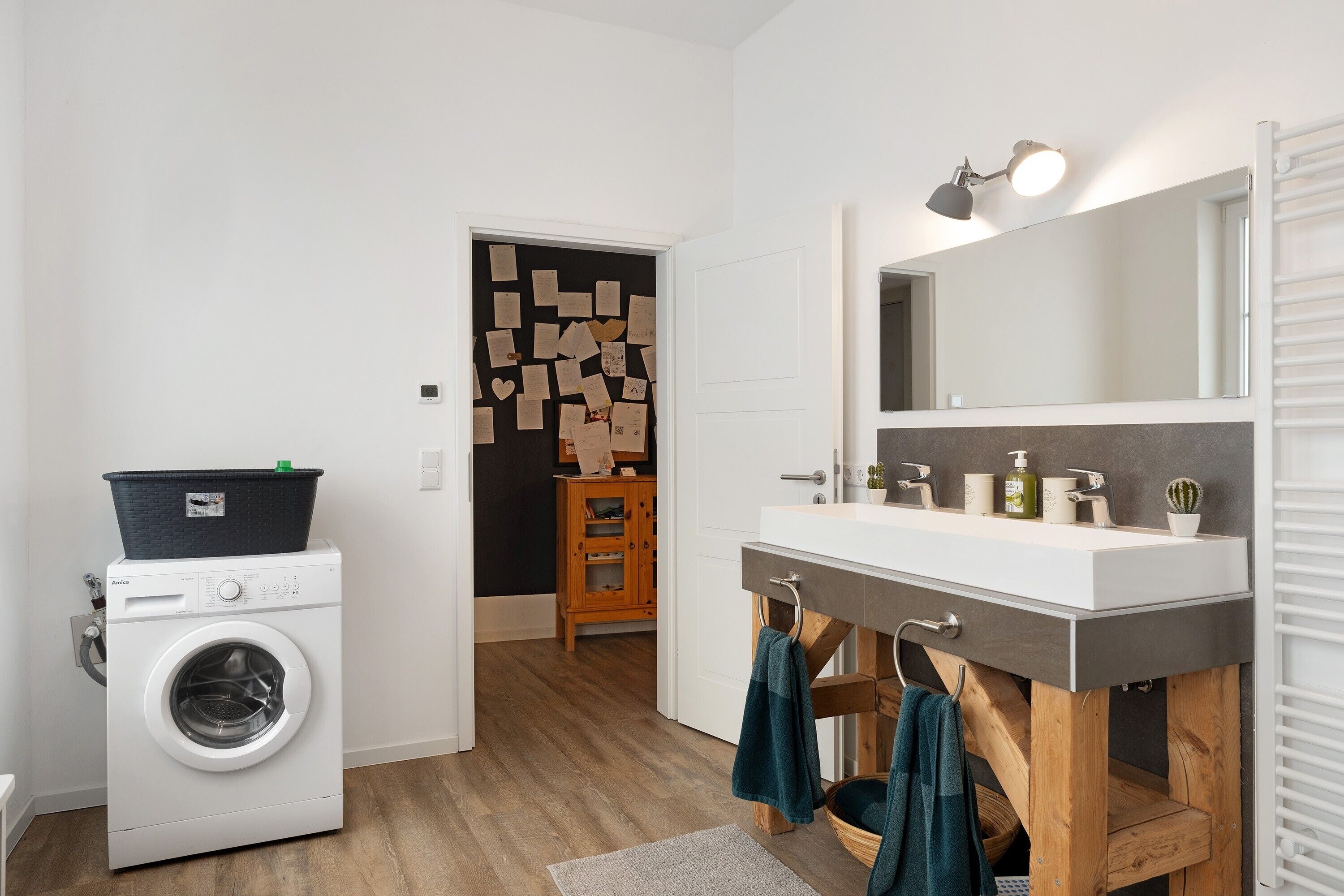 Ein modernes Badezimmer mit Waschmaschine, Waschbecken mit Spiegel und Holzschrank.