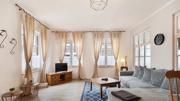 A living room with a sofa, a coffee table, a TV, and curtains.