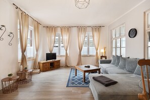 A living room with a sofa, a coffee table, a TV, and curtains.