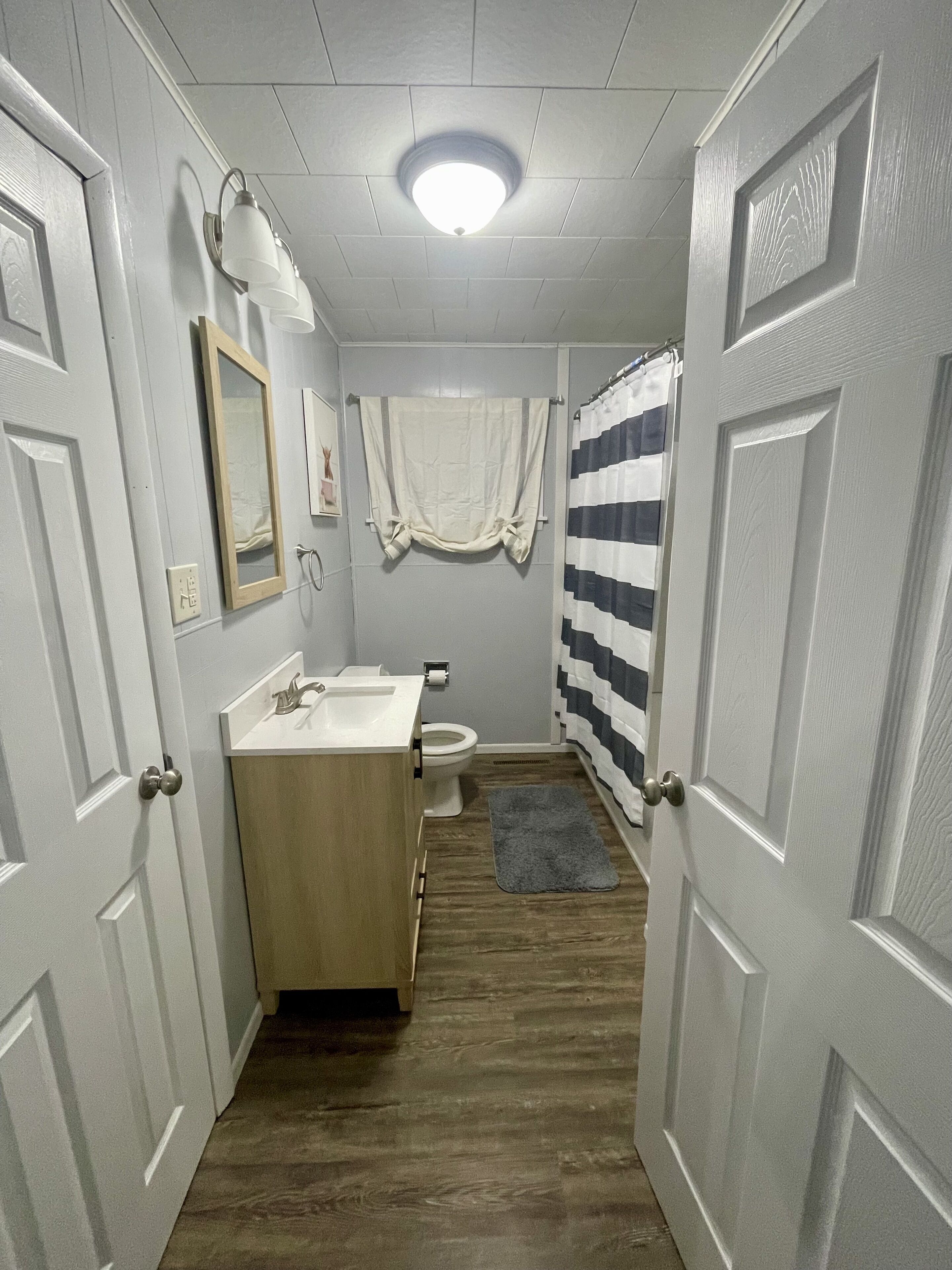 Une petite salle de bain avec un meuble-lavabo en bois, des toilettes et un rideau de douche.