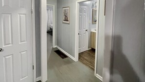 A hallway with white doors, a light fixture, and a framed picture on the wall.