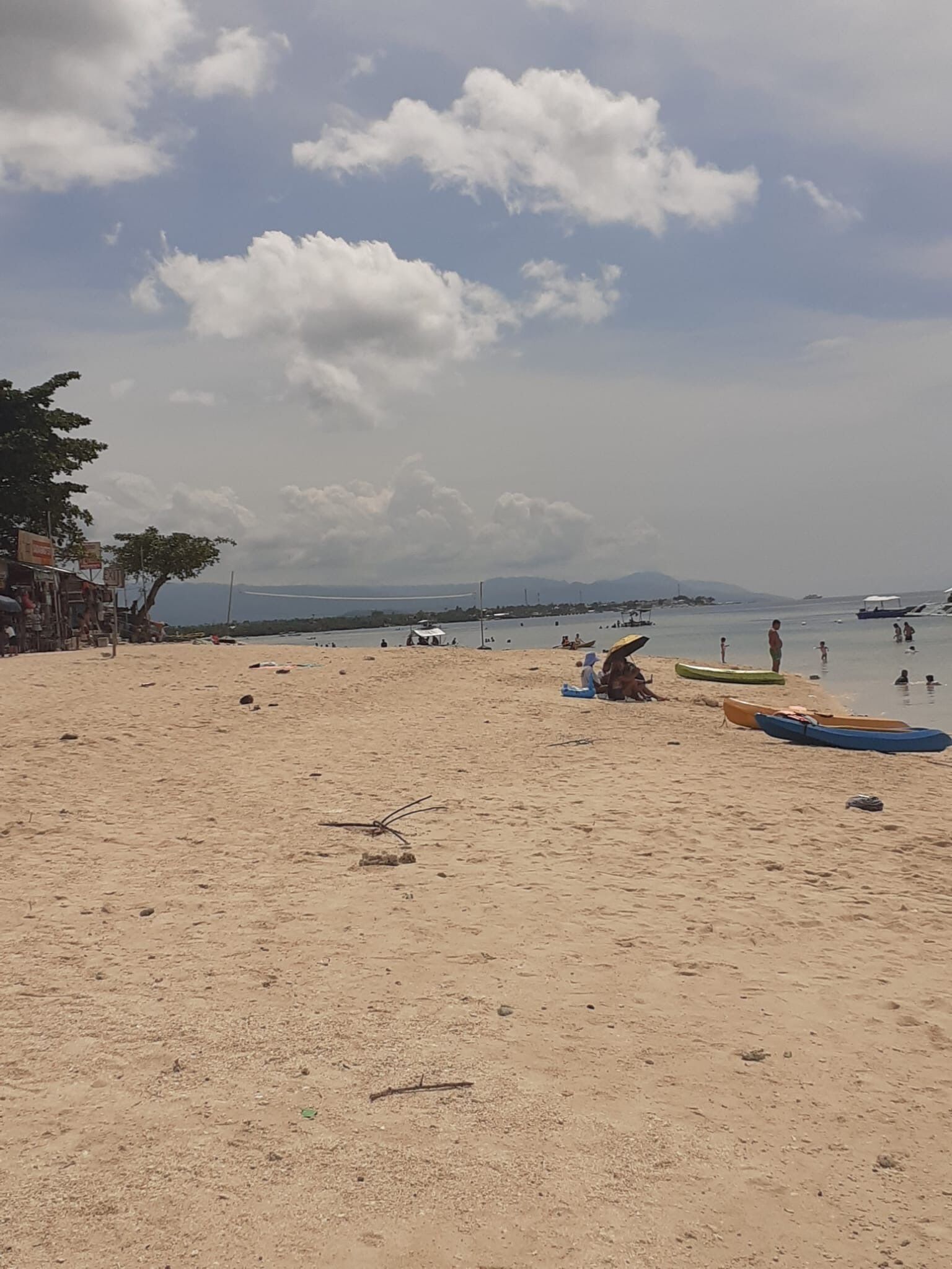A sandy beach with boats and people.
