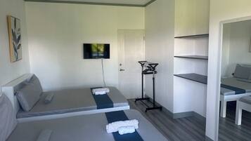 A hotel room with two beds, a TV mounted on the wall, a ceiling fan, and a mirror.