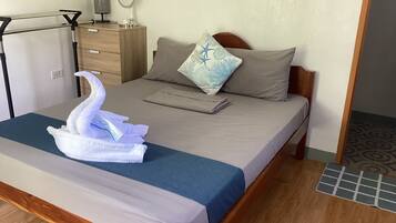Una cama bien hecha con una colcha azul, un cabecero de madera y una toalla decorativa con forma de cisne.