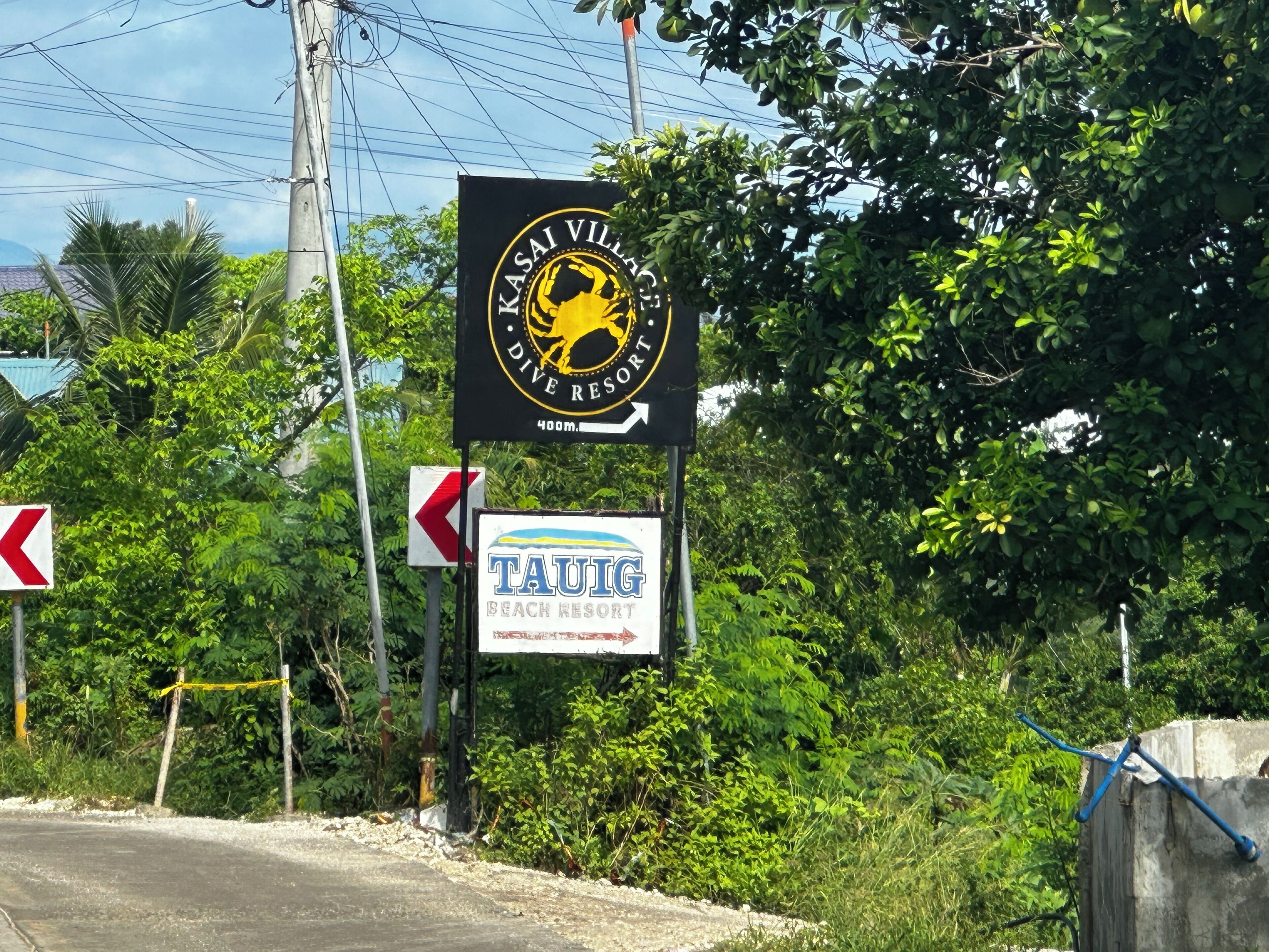 Señalización para Kasai Village Dive Resort, con una flecha direccional, y una señalización para Tauig Beach Resort.