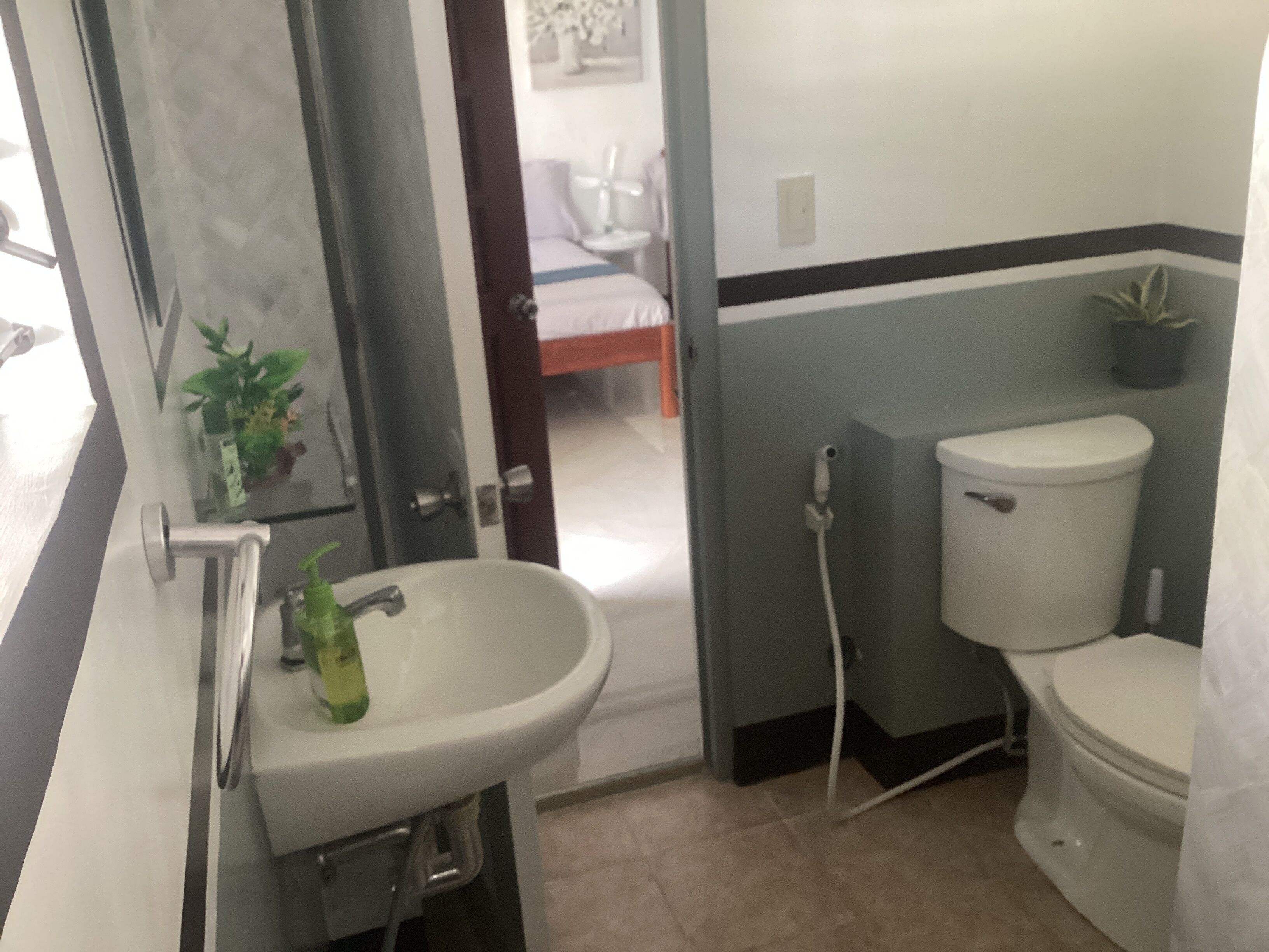 A bathroom with a sink, toilet, and a door leading to a bedroom.