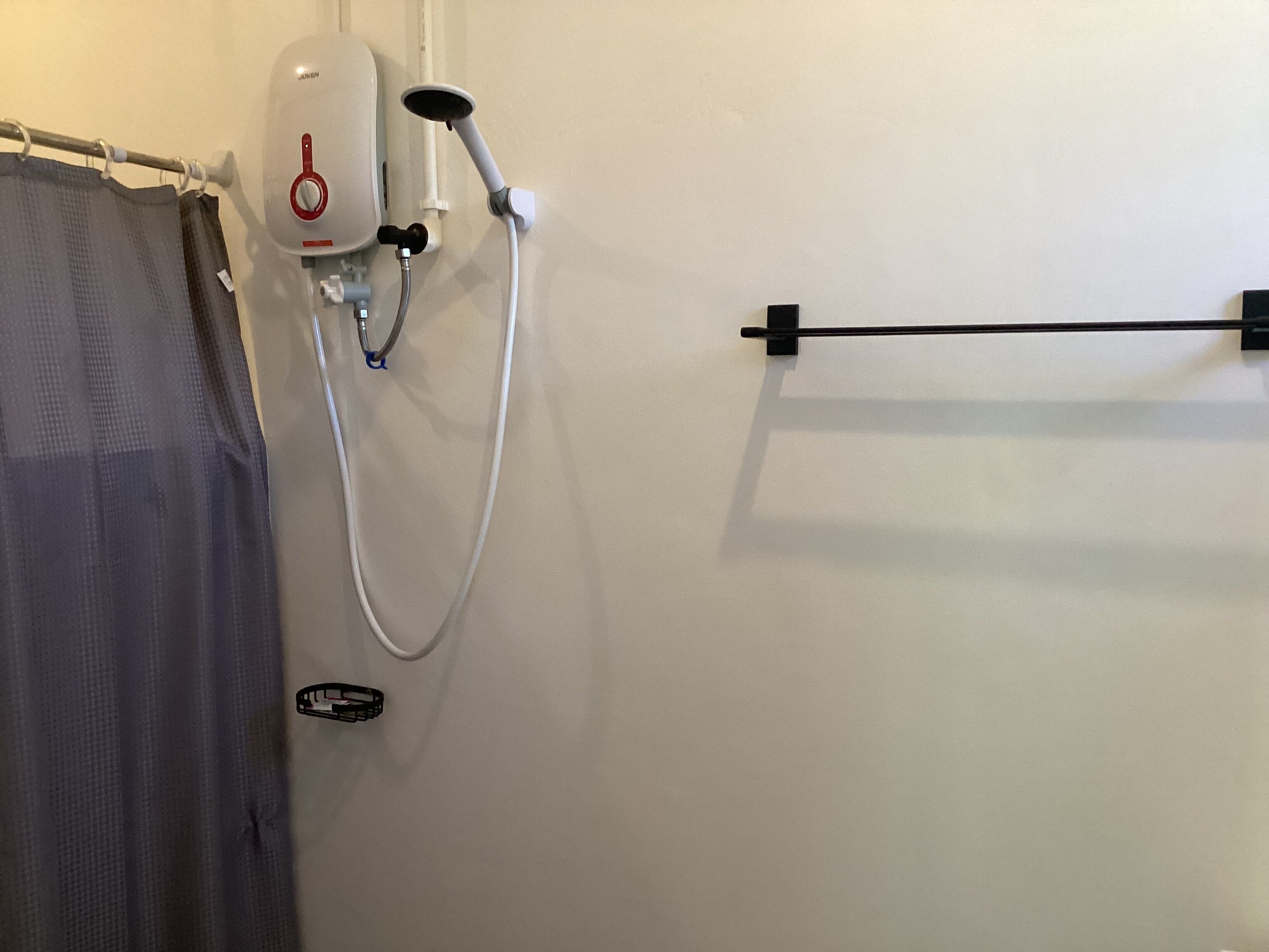 A bathroom with a shower, a towel rack, and a curtain.