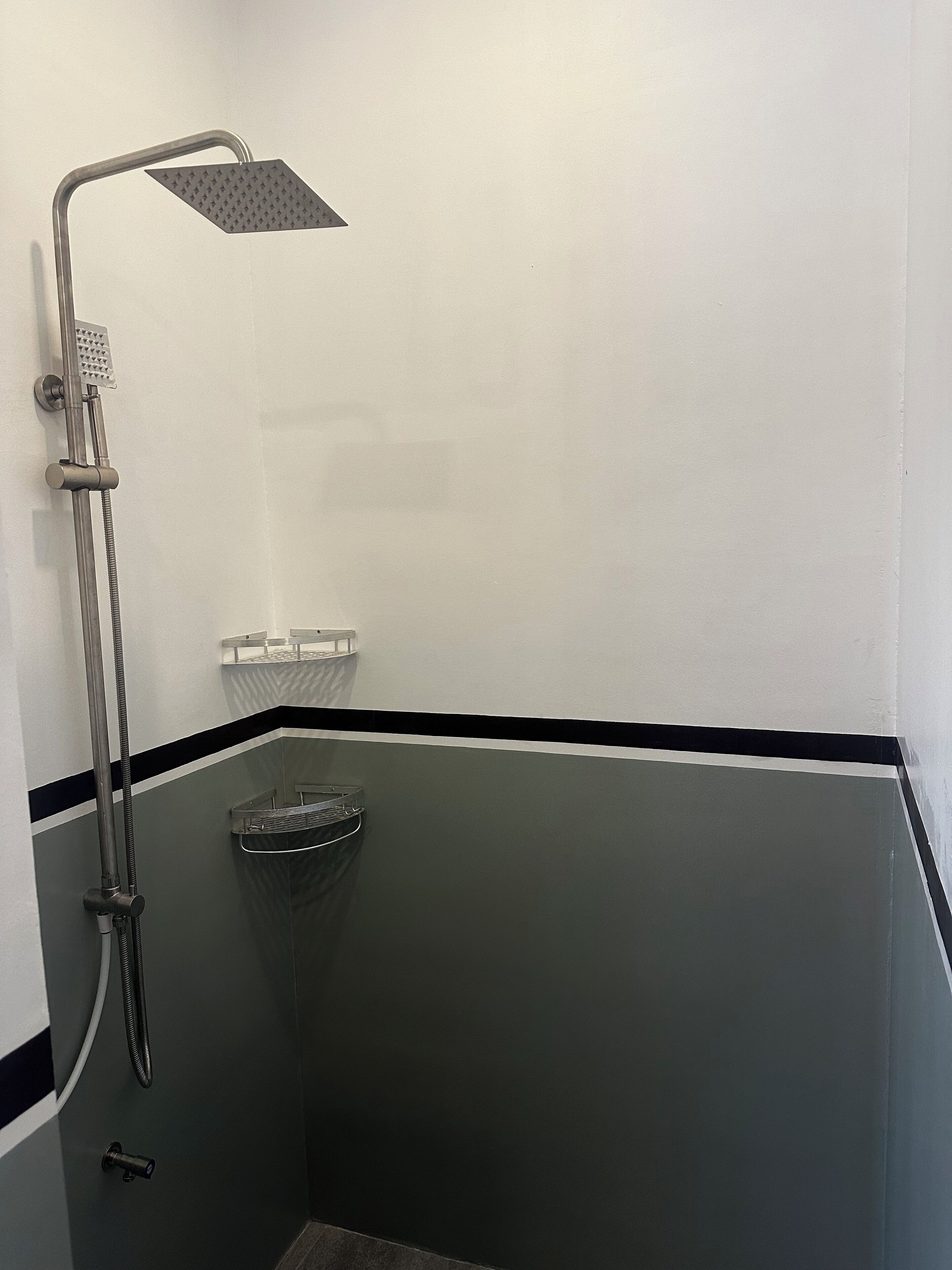 Een douchehoek met een handdouche en een wandmengkraan.