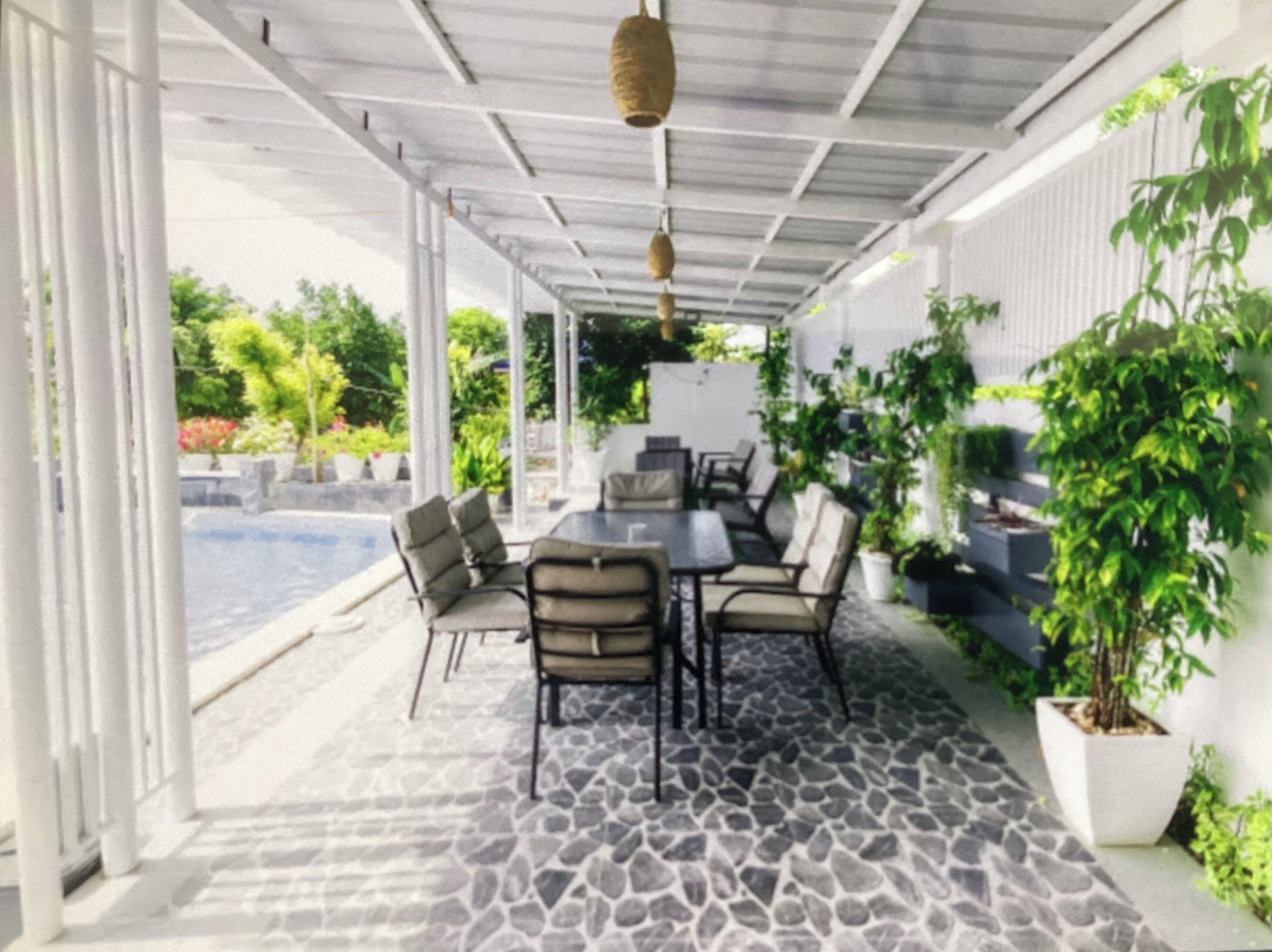 An outdoor patio area with a stone floor, seating, and potted plants.