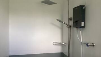 A shower with a handheld showerhead, a wall-mounted faucet, and a control box.