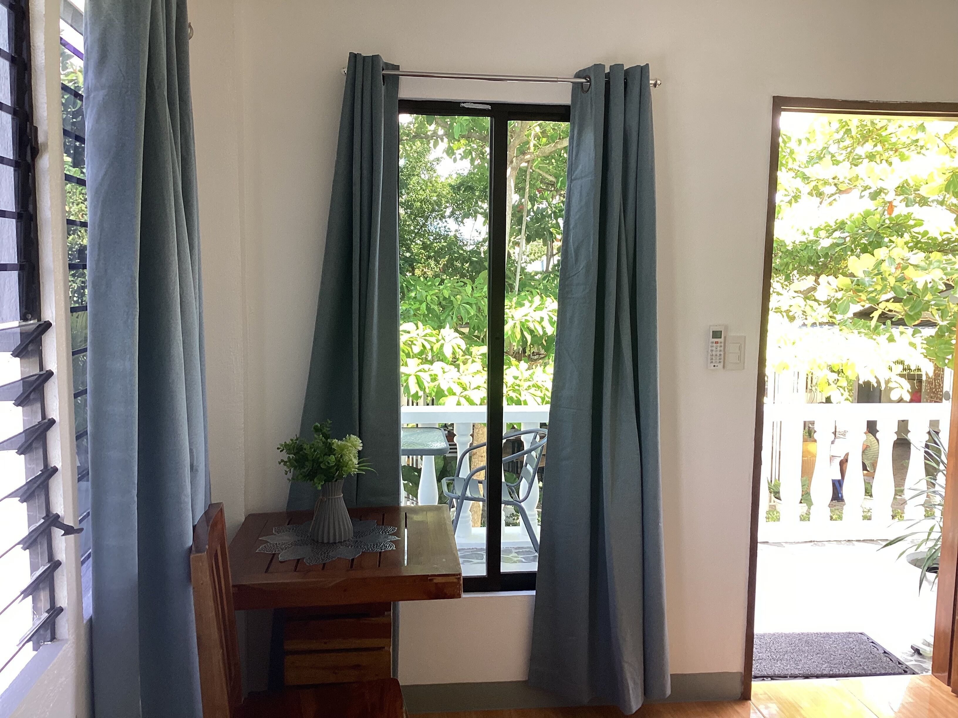 A room with a wooden table, a potted plant, and a window with curtains.
