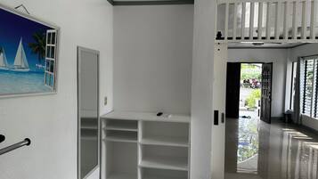 A hallway with a white wall, a door, and a shelf unit.