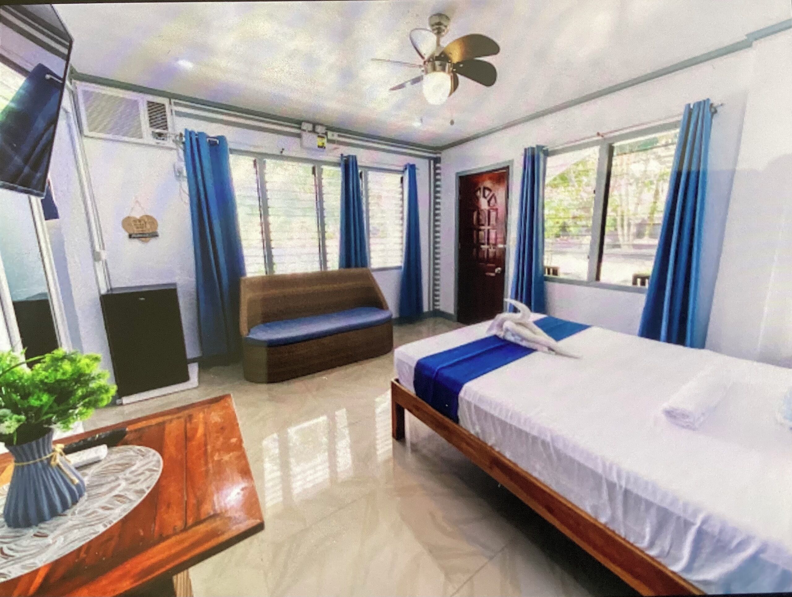 A hotel room with a bed, a sofa, a desk, and a TV.