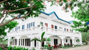 A white building with a blue roof, multiple balconies, and a covered patio area with chairs. - Moalboal Casablanca Inn  (Moalboal)