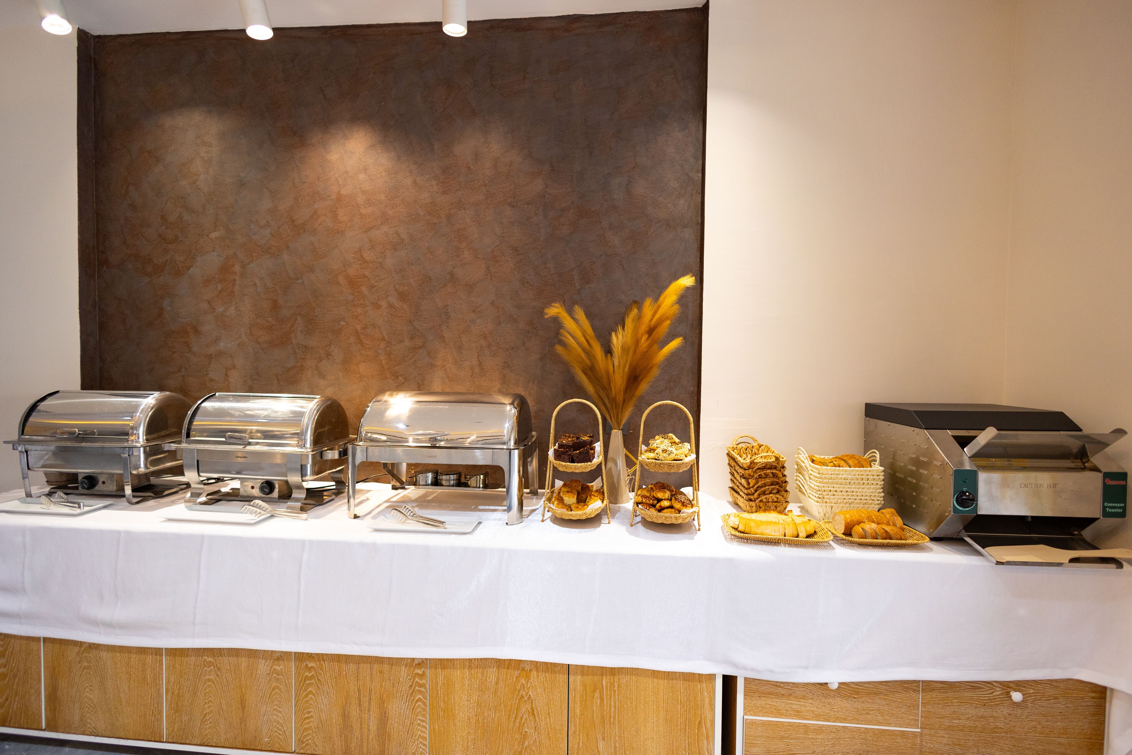 Disposição de buffet com diversas estações de comida e uma máquina de pão.