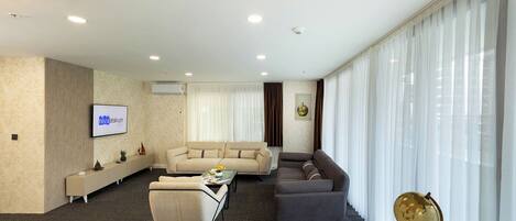 A modern living room with a sofa set, a coffee table, and a TV mounted on the wall.