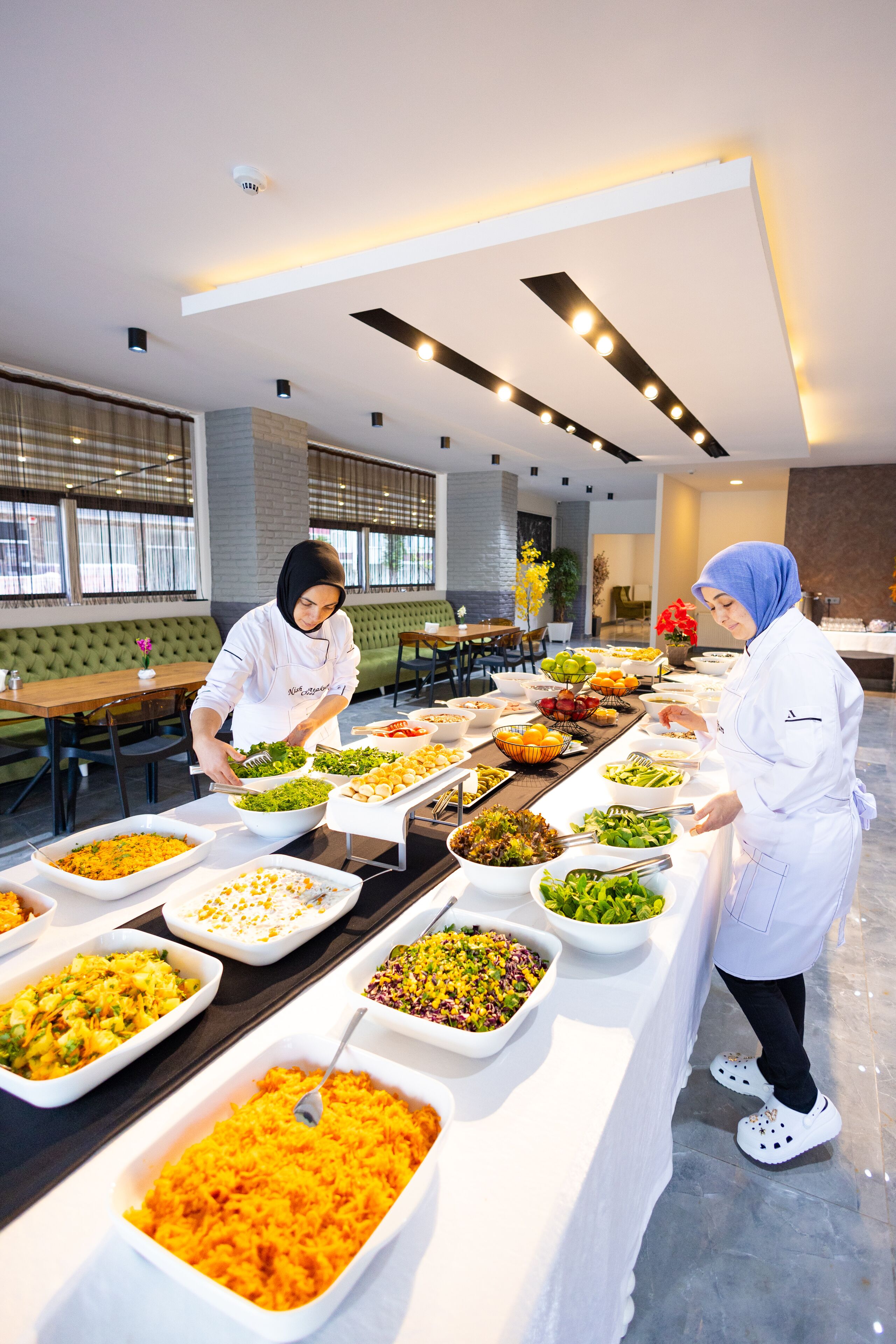 A buffet setup with various food items and a person serving.