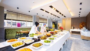 A buffet setup with various food items and a green upholstered sofa in the background.