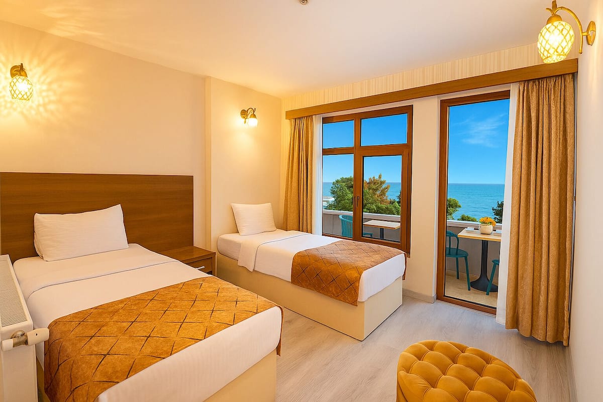 Ein Hotelzimmer mit zwei Betten, einem kleinen Tisch, einem Stuhl und Blick aufs Meer.