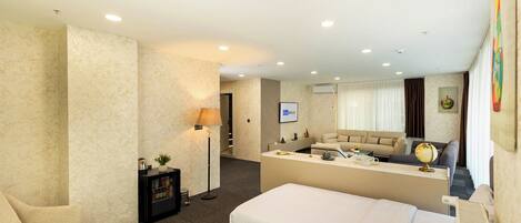 A hotel room with a bed, a desk, a sofa, a lamp, and a globe.