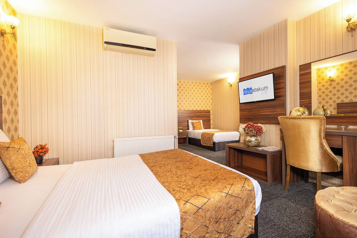 Ein Hotelzimmer mit zwei Betten, einem Schreibtisch, einem Stuhl, einem Fernseher und einer Wandklimaanlage.