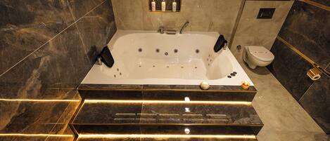 A modern bathroom with a freestanding bathtub, a toilet, and a small potted plant on the wall.