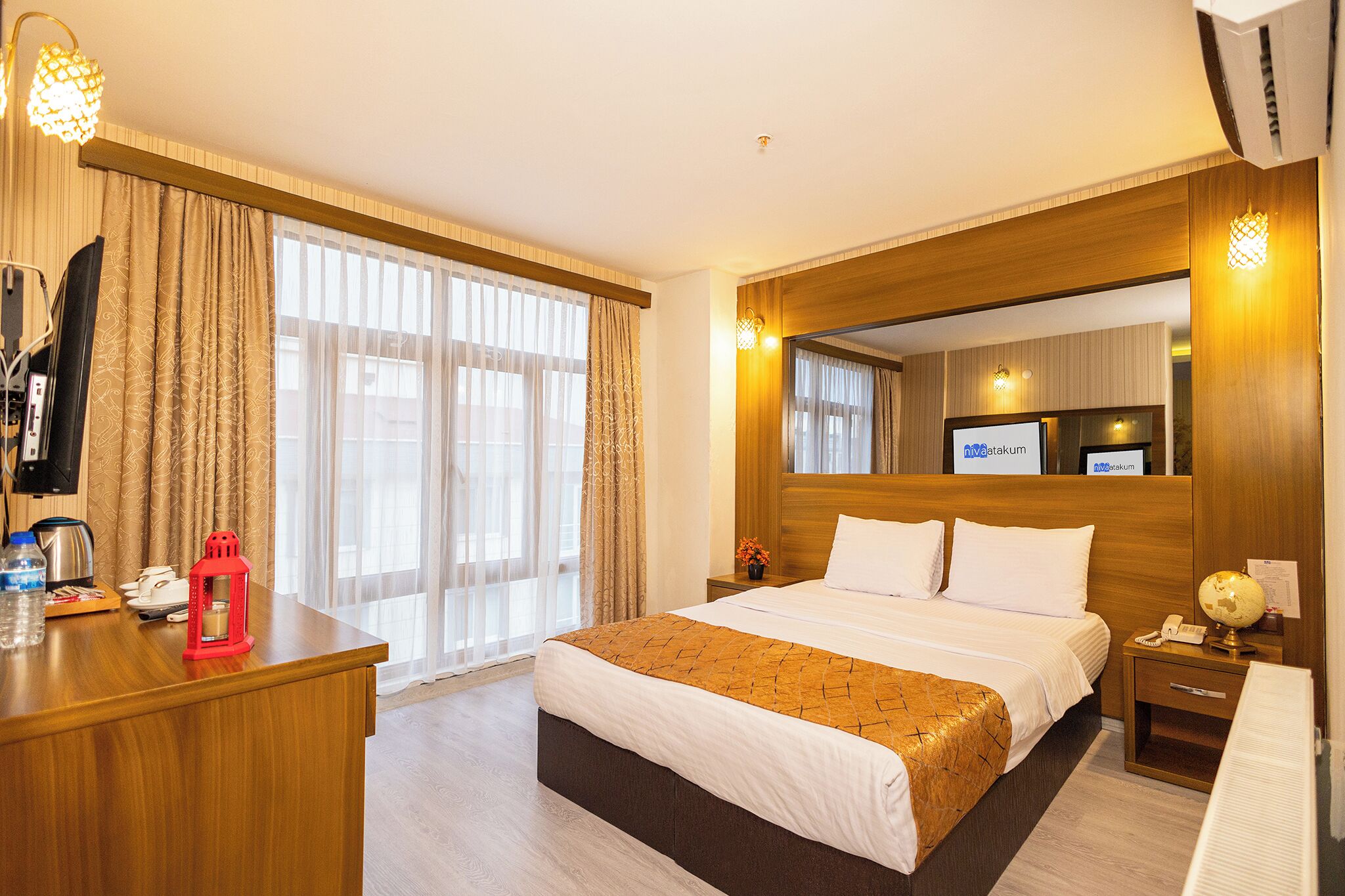 A hotel room with a large bed, a wooden desk, a television, and a minibar.