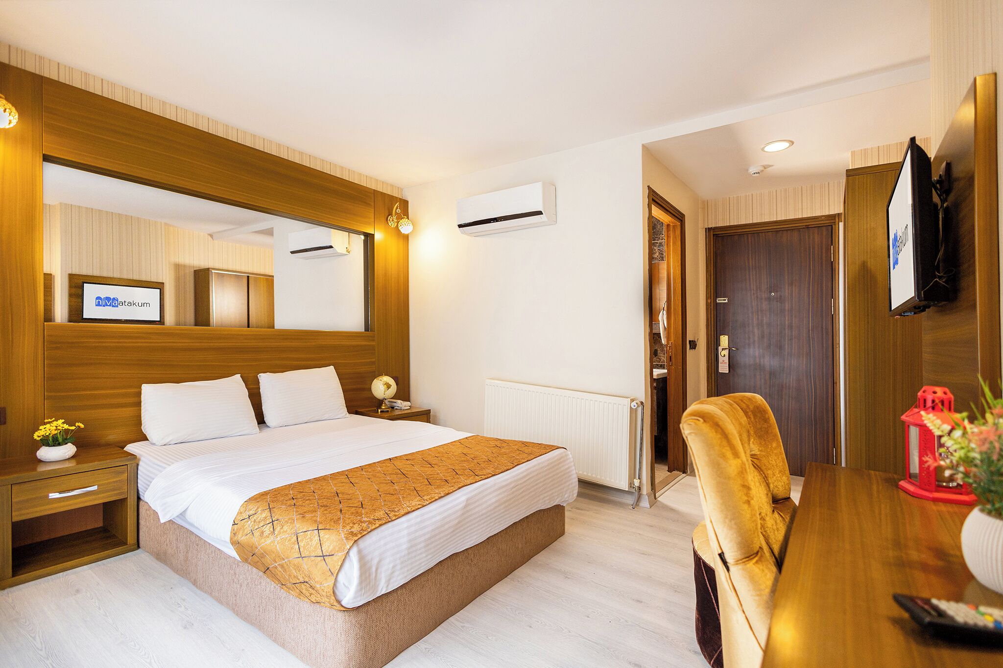 A hotel room with a large bed, bedside table, nightstand, and a TV mounted on the wall.