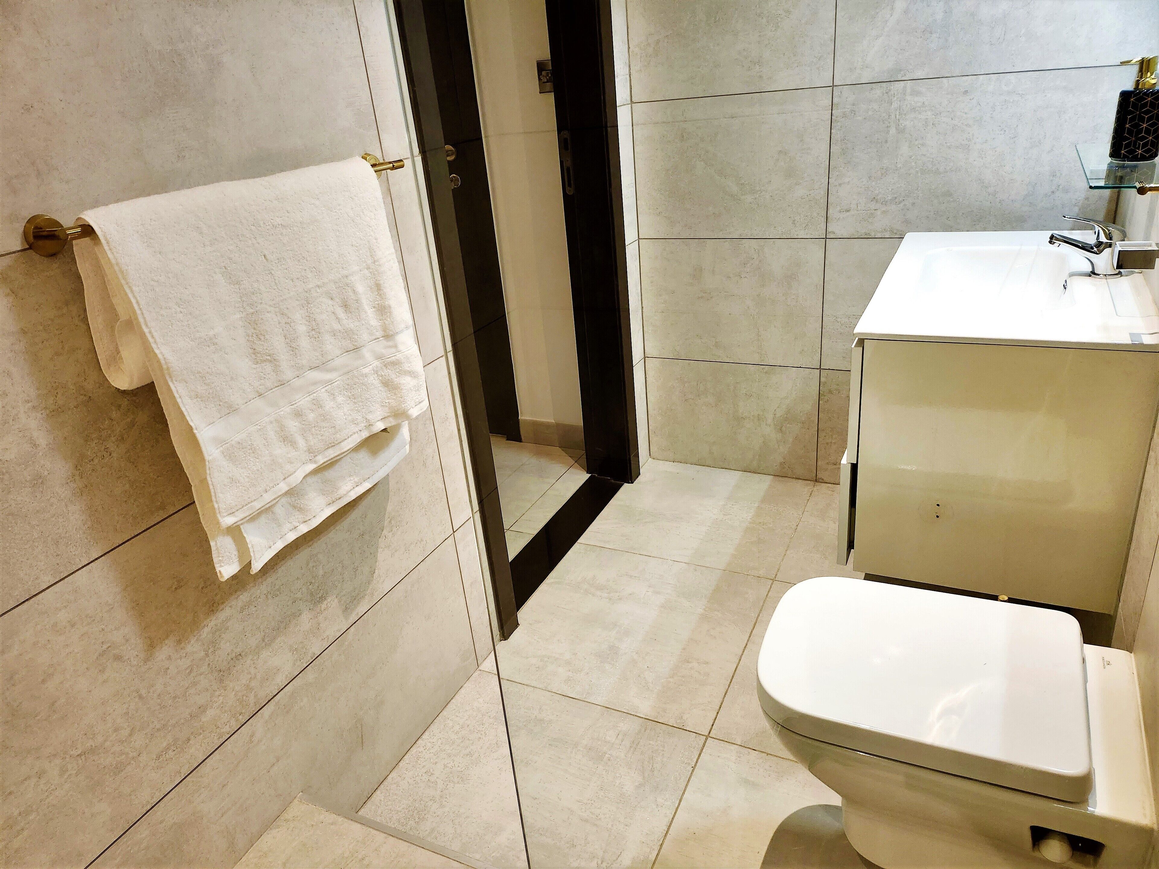 Un baño con inodoro, lavabo y toallero.