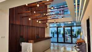 A modern reception area with a wooden slatted wall, a reception desk, and a glass door leading outside.