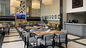 Un restaurante moderno con sillas a cuadros, lámparas colgantes y una pantalla de televisión que muestra un paisaje nevado.