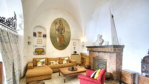 Un salon avec un canapé, des fauteuils, une cheminée et un tableau au mur.
