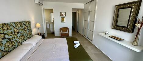 Una habitación de hotel con cama, una silla, tocador y espejo.