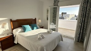 Une chambre d’hôtel avec un lit, une table de chevet, une lampe, une fenêtre avec des rideaux et une vue sur l’extérieur.