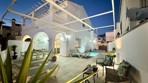 Un espace extérieur aménagé avec une terrasse, une piscine, des sièges et une pergola.
