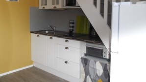 A compact kitchen with white cabinets, a microwave, a coffee maker, and a refrigerator.