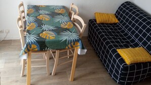 A room with a dining table and chairs, a sofa, and a small wall-mounted heater.
